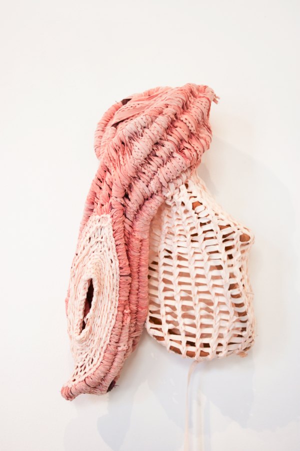 Basket Body by Katie Shulman: a coiled wall sculpture in coral pink and pale peach, one side tightly wrapped, the other an open lattice like basketry